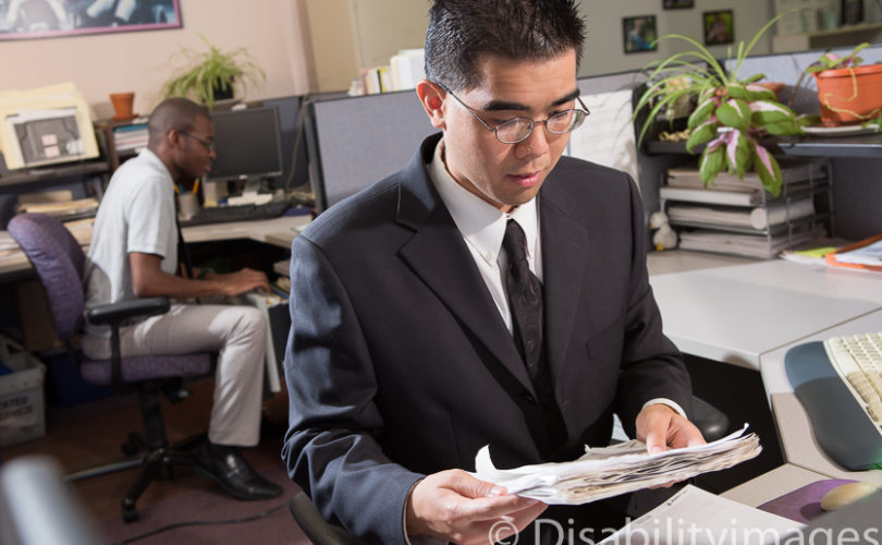Young adult in a suit files papers in an office