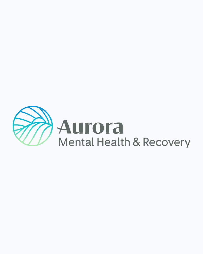 The logo is an image of a teal circle with the sun rising over blue colored mountains. Next to the image are the words Aurora Mental Health and Recovery in gray lettering.